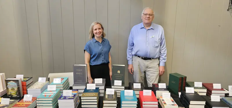 Two booksellers standing behind the conference book table, stacked with Reformed titles