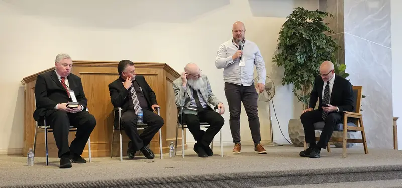 Panel of speakers seated on the platform during the question-and-answer session, with a moderator standing to relay a question